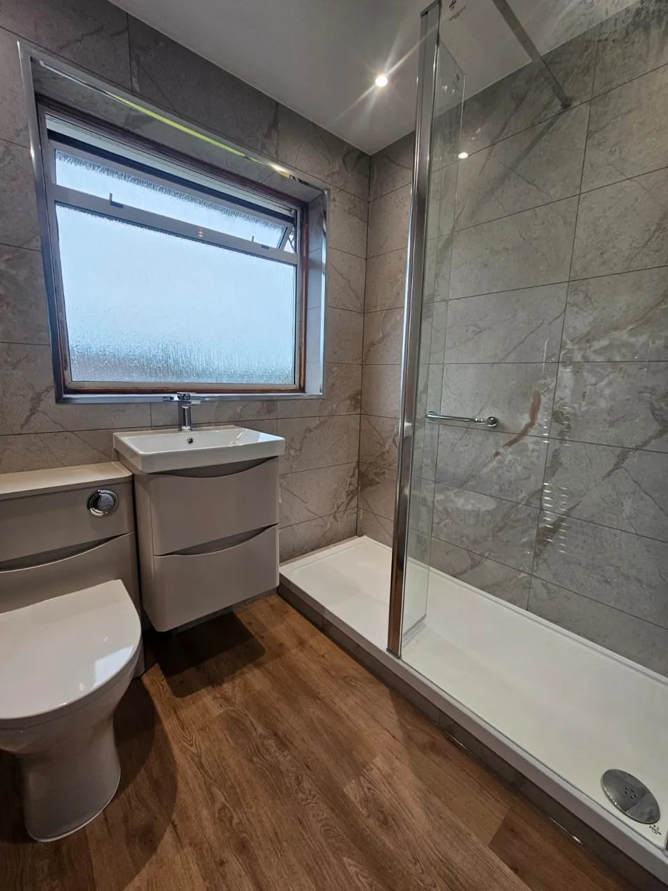 Shower room with white vanity and wood-effect flooring